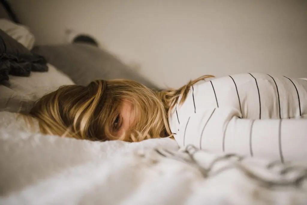 Eine Frau liegt im Bett mit offenen Augen und zerzausten Haaren.